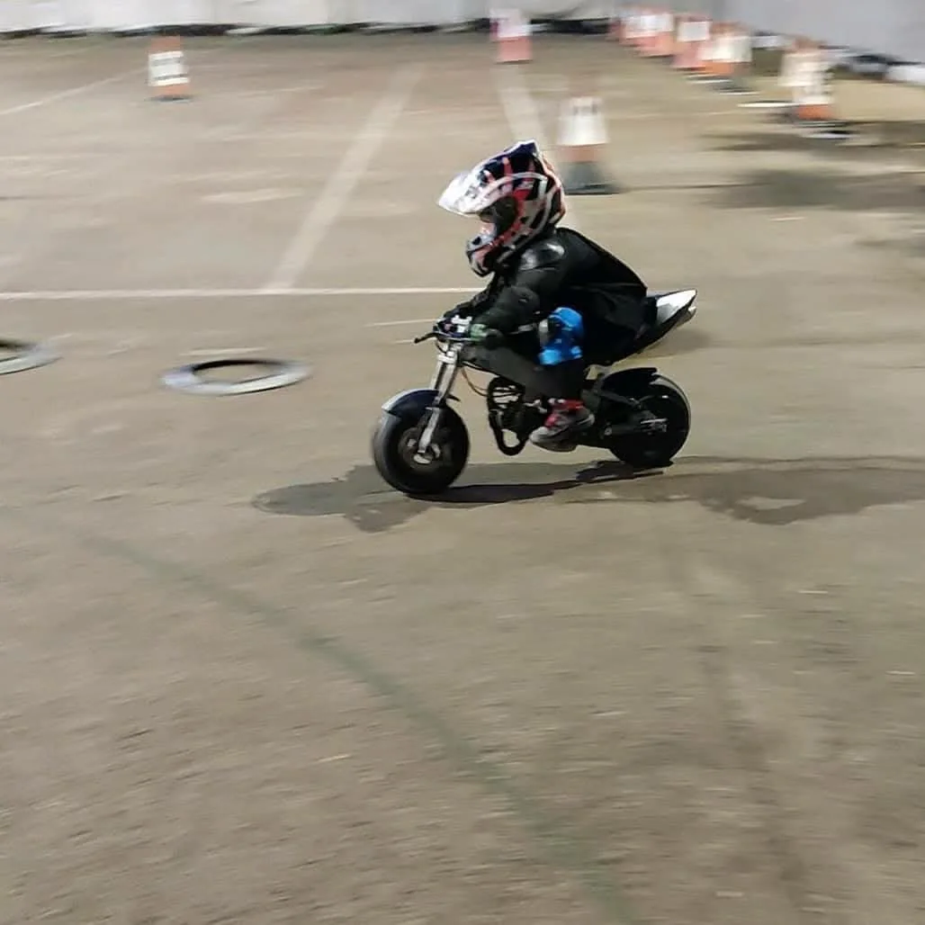 Joven piloto conduciendo una minimoto en circuito