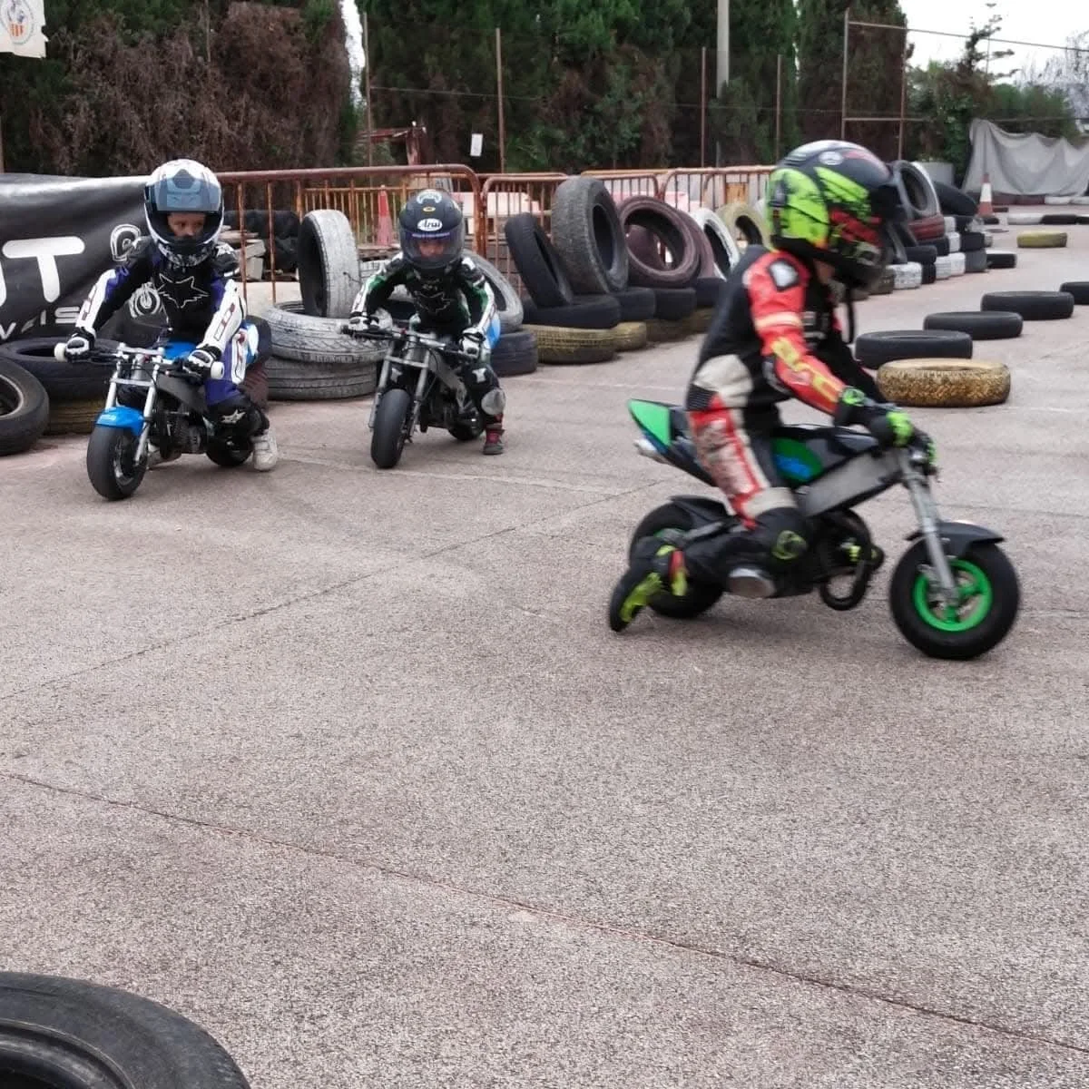 Niños entrenando con minimotos en un circuito delimitado